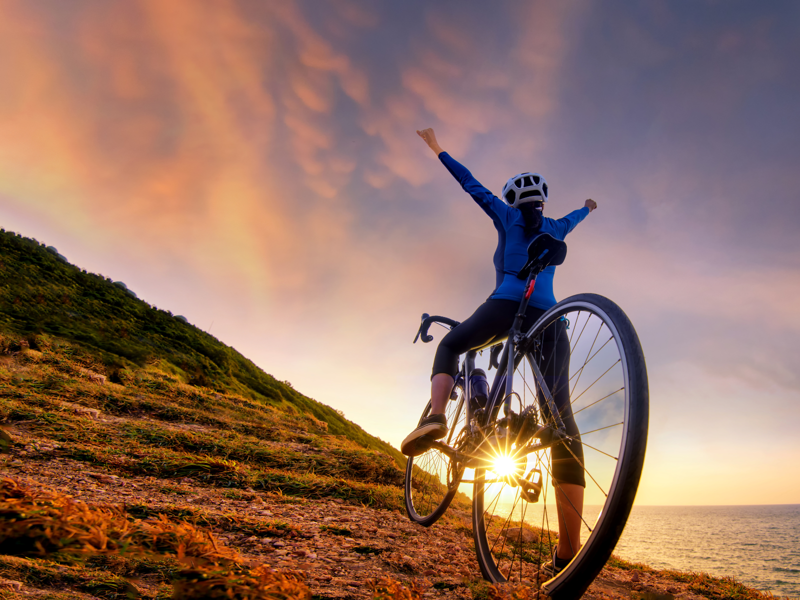 Mindfulness entdecken: Lebendig fühlen durch Achtsamkeit Frau erklimmt bei Sonnenuntergang mit ihrem Fahrrad einen Berg und fühlt sich lebendig.