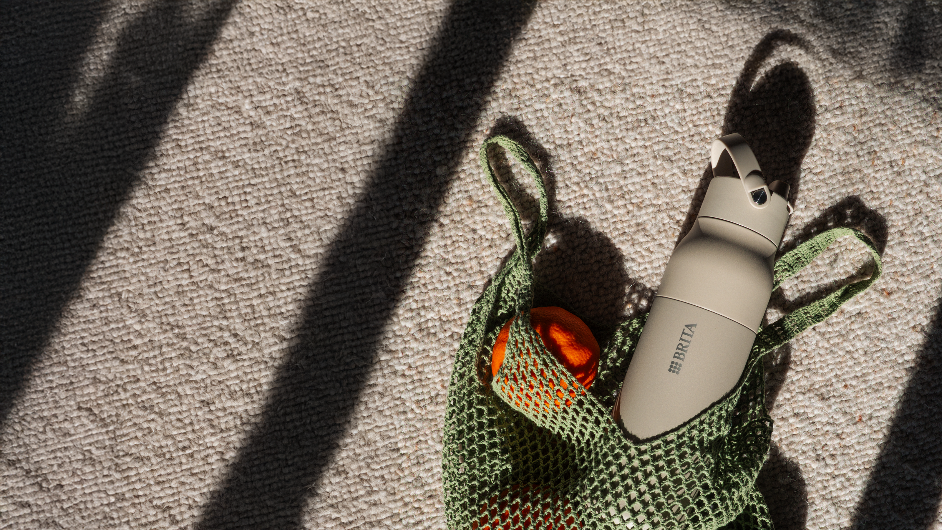 Einkauf mit Mandarinen und beige BRITA LARQ iQ Flasche in grüner Einkaufstasche