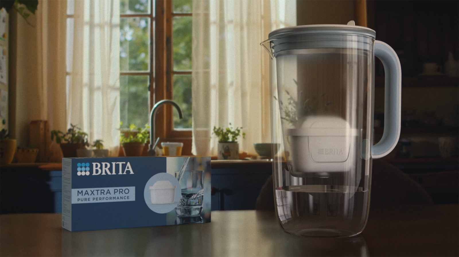 Eine Verpackung MAXTRA PRO Pure Performance Wasserfilter neben einem Tischwasserfilter Glas in Küche