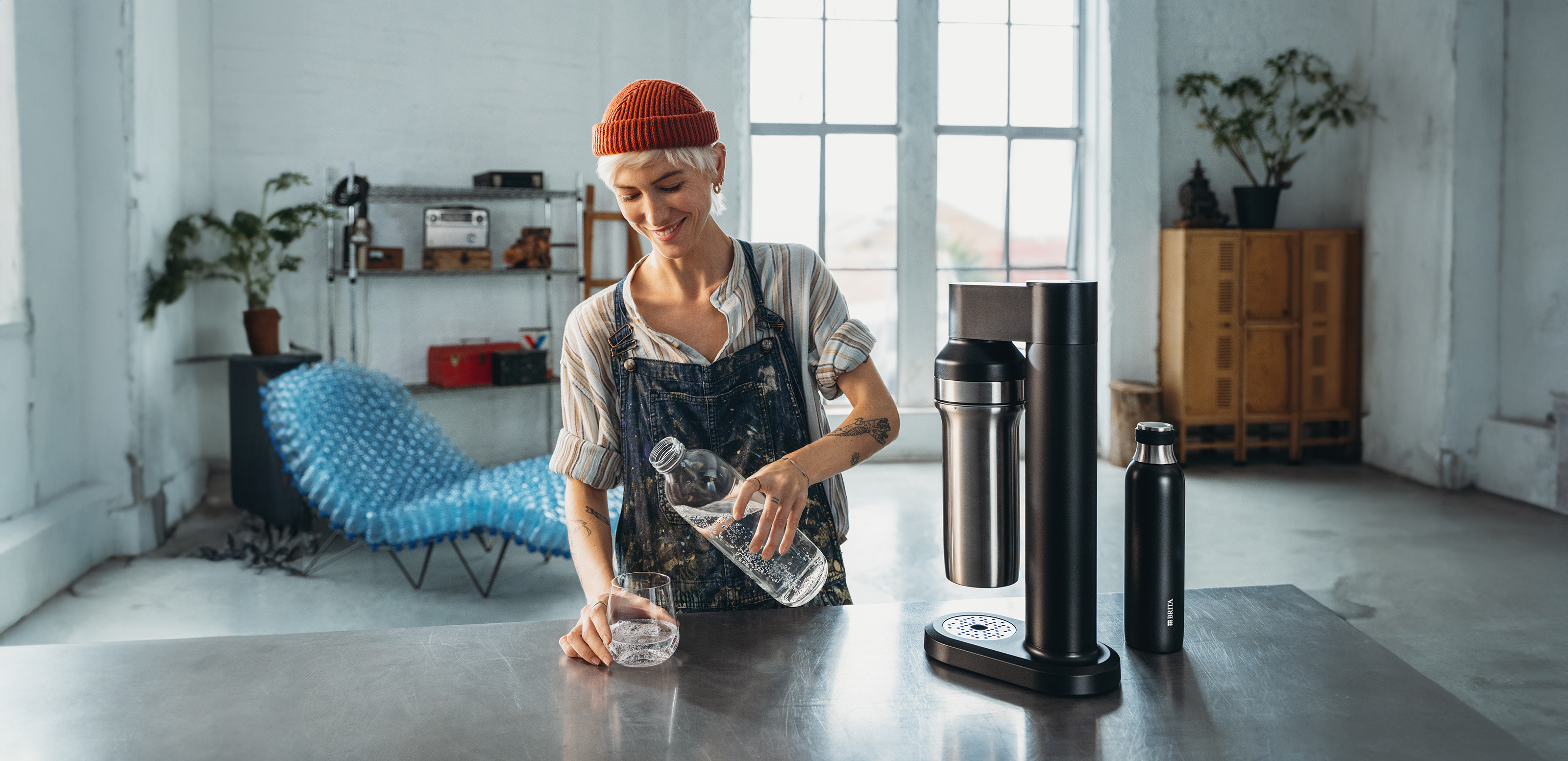 Frau gießt sich ein Glas Wasser ein neben dem BRITA sodaTRIO Wassersprudler.