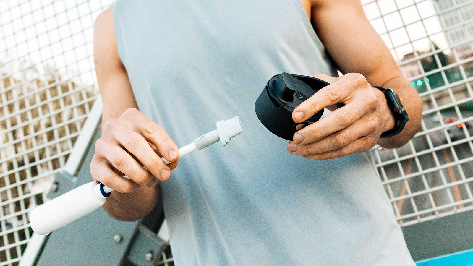 Ein junger Mann im Sportoutfit hält den Deckel und den Filter Straw der BRITA LARQ iQ in der Hand.
