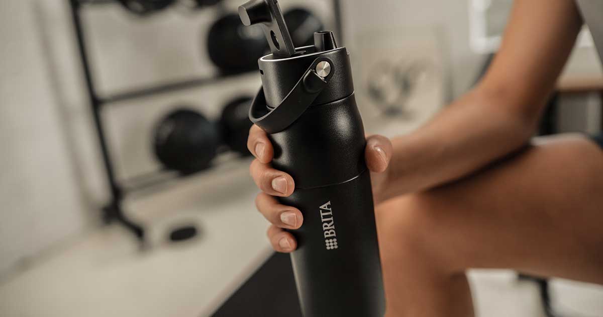 Person hält eine schwarze BRITA LARQ Bottle im Fitnessstudio in der Hand.