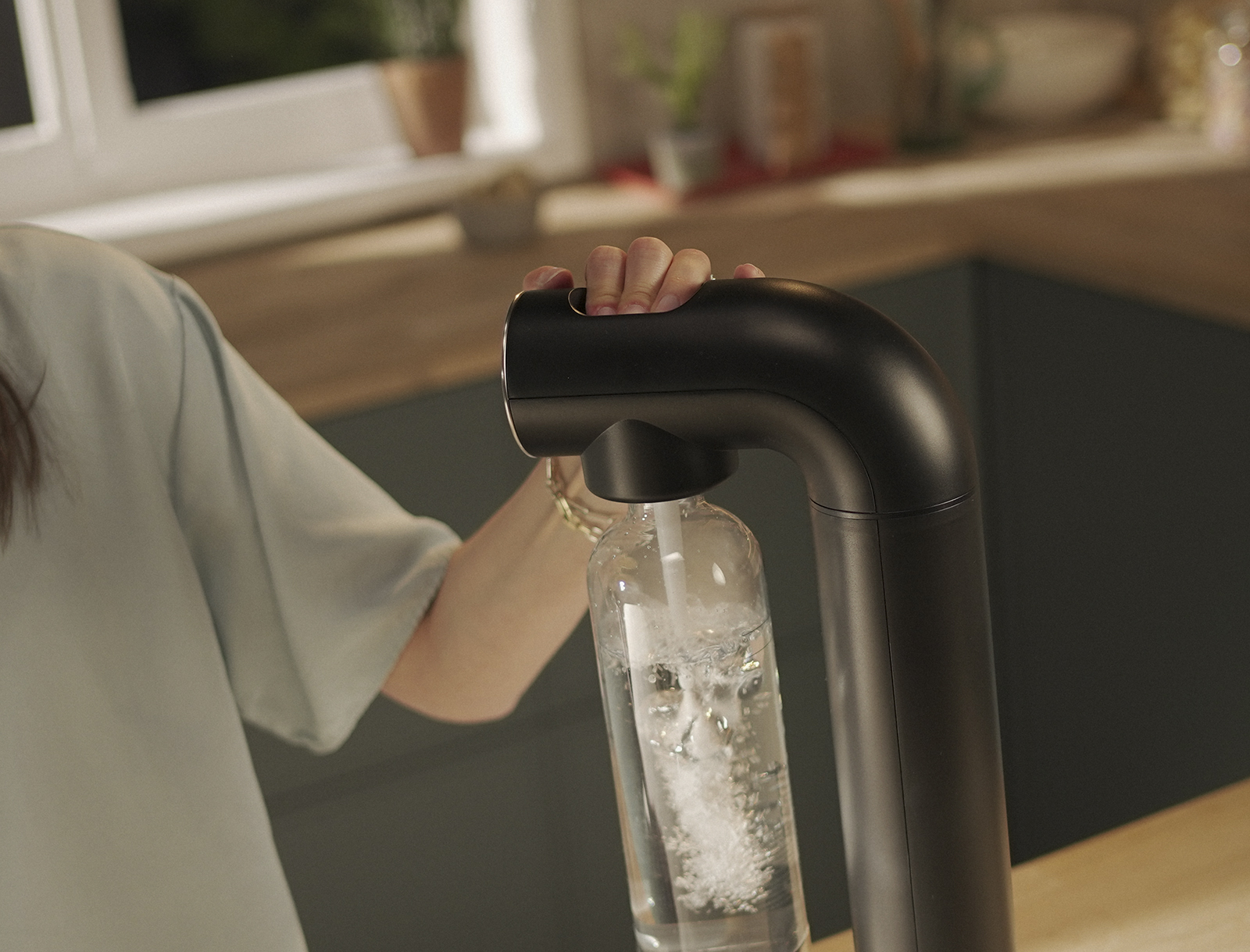 Eine Frau drückt auf den Knopf zum Sprudeln am schwarzen BRITA sodaONE