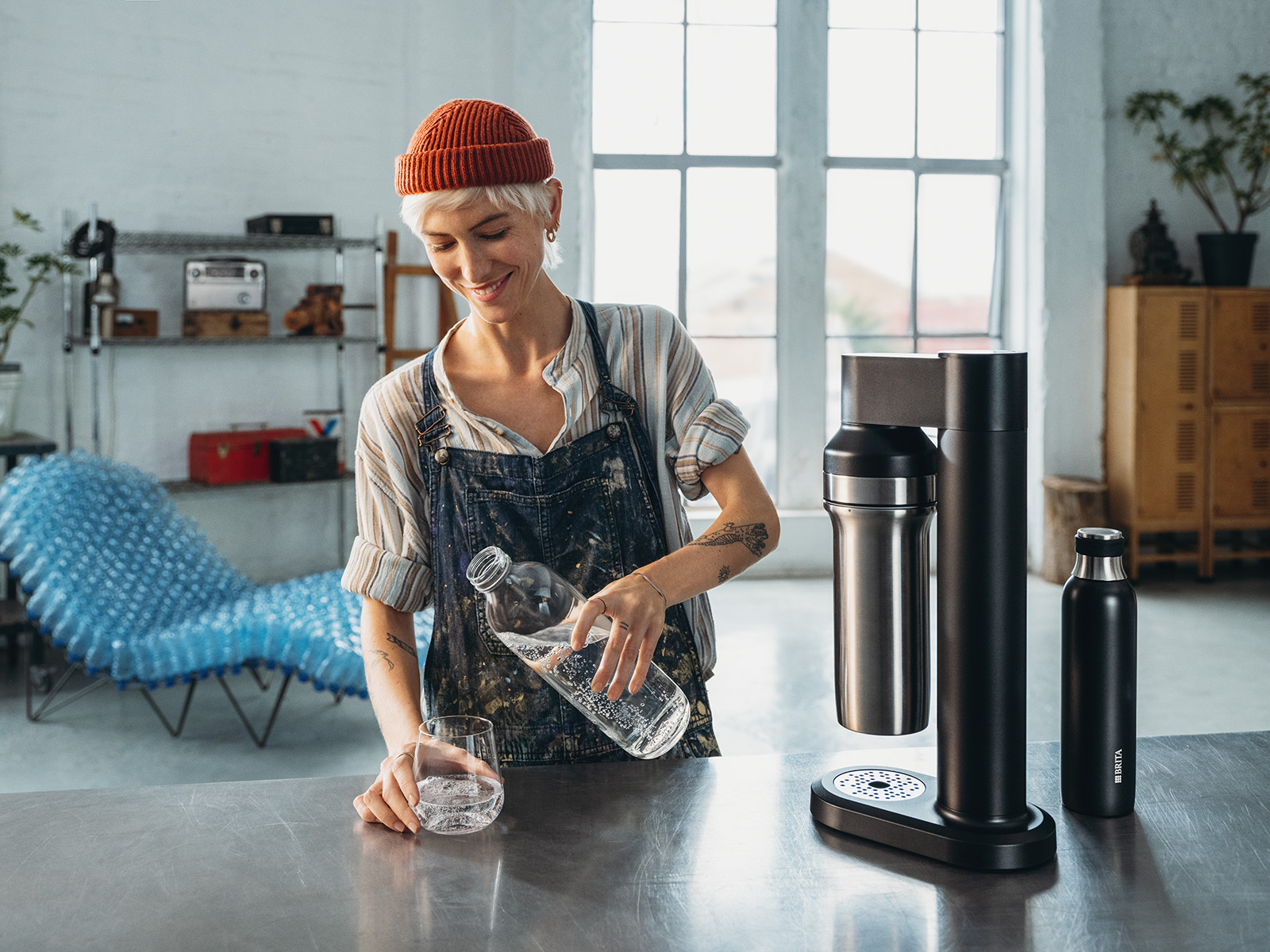 Frau gießt sich ein Glasser Wasser ein neben sodaTRIO. Frau gießt sich ein Glasser Wasser ein neben dem BRITA sodaTRIO Wassersprudler