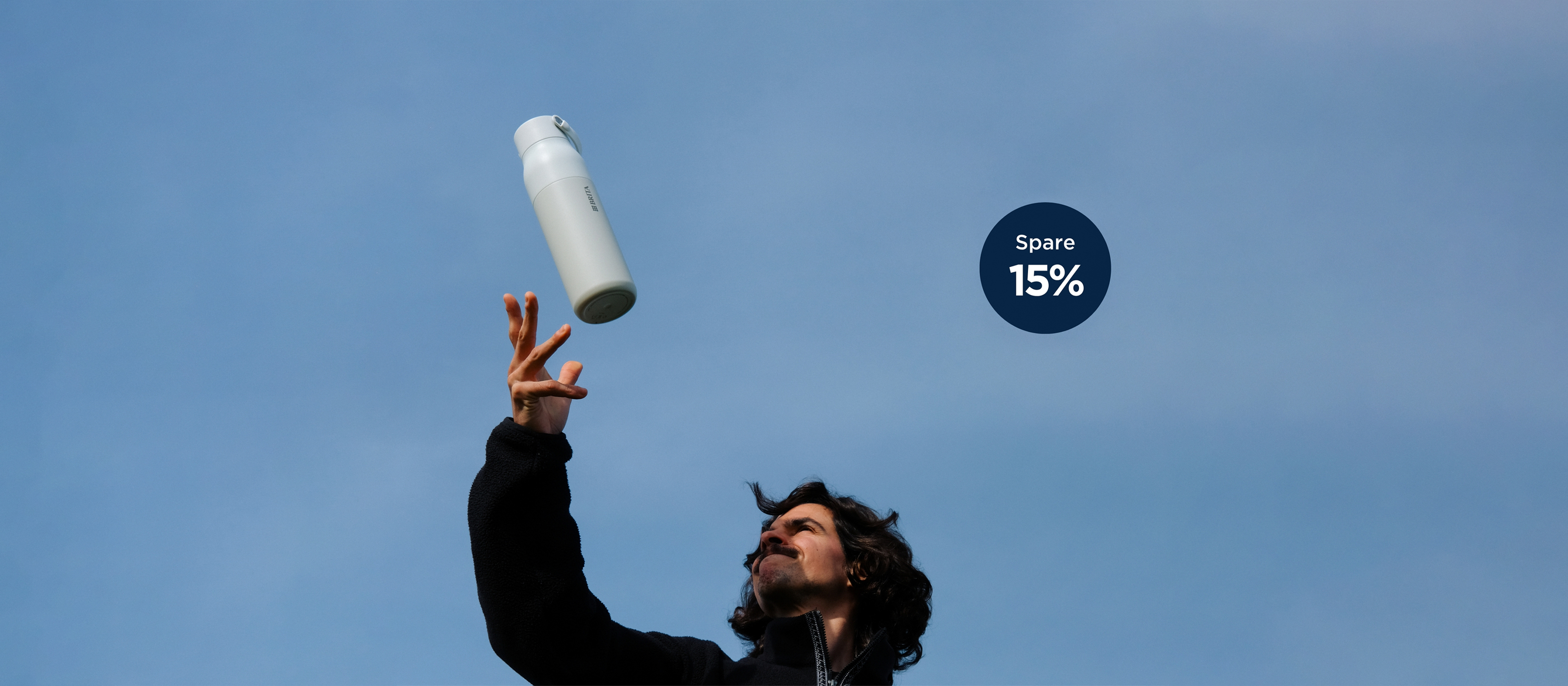 Ein junger Mann wirft freudig eine weiße BRITA LARQ Filterflasche in die Luft.
