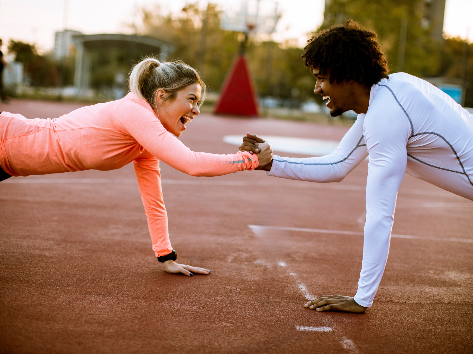Outdoor-Workout - Sport im Freien Eine junge Frau und ein junger Mann trainieren gerade die Plank und halten sich gegenseitig