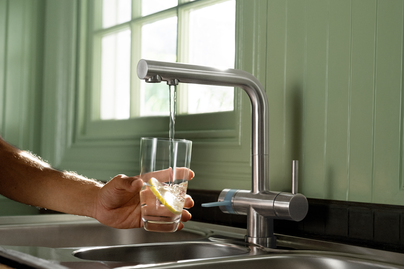 Gefiltertes Leitungswasser läuft aus dem BRITA 3-Wege-Hahn Gefiltertes Leitungswasser läuft aus dem BRITA 3-Wege-Hahn in ein Glas