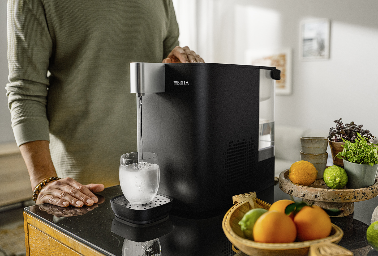 Ein Mann füllt sich ein Glas mit eiskaltem Wasser aus dem BRITA Cube Cool Wasserspender.
