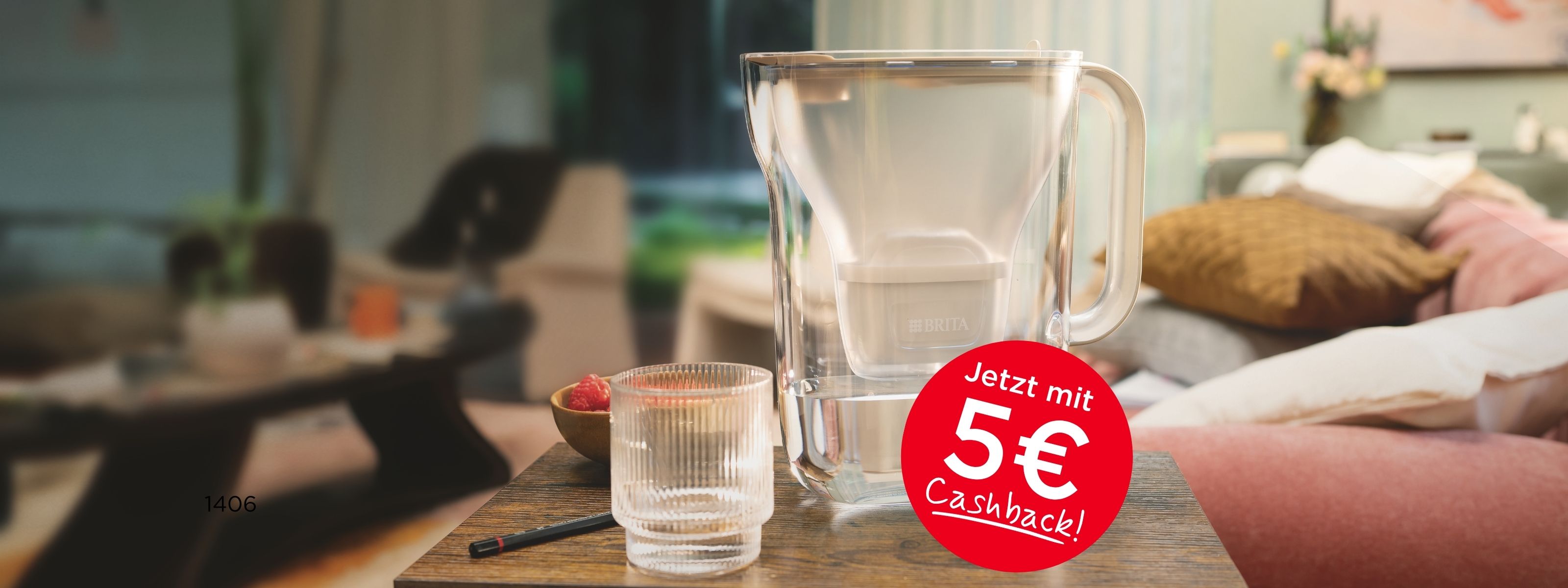 BRITA Style Essential steht mit einem Wasserglas auf dem Couchtisch. Störer: Jetzt mit 5€ Cashback.
