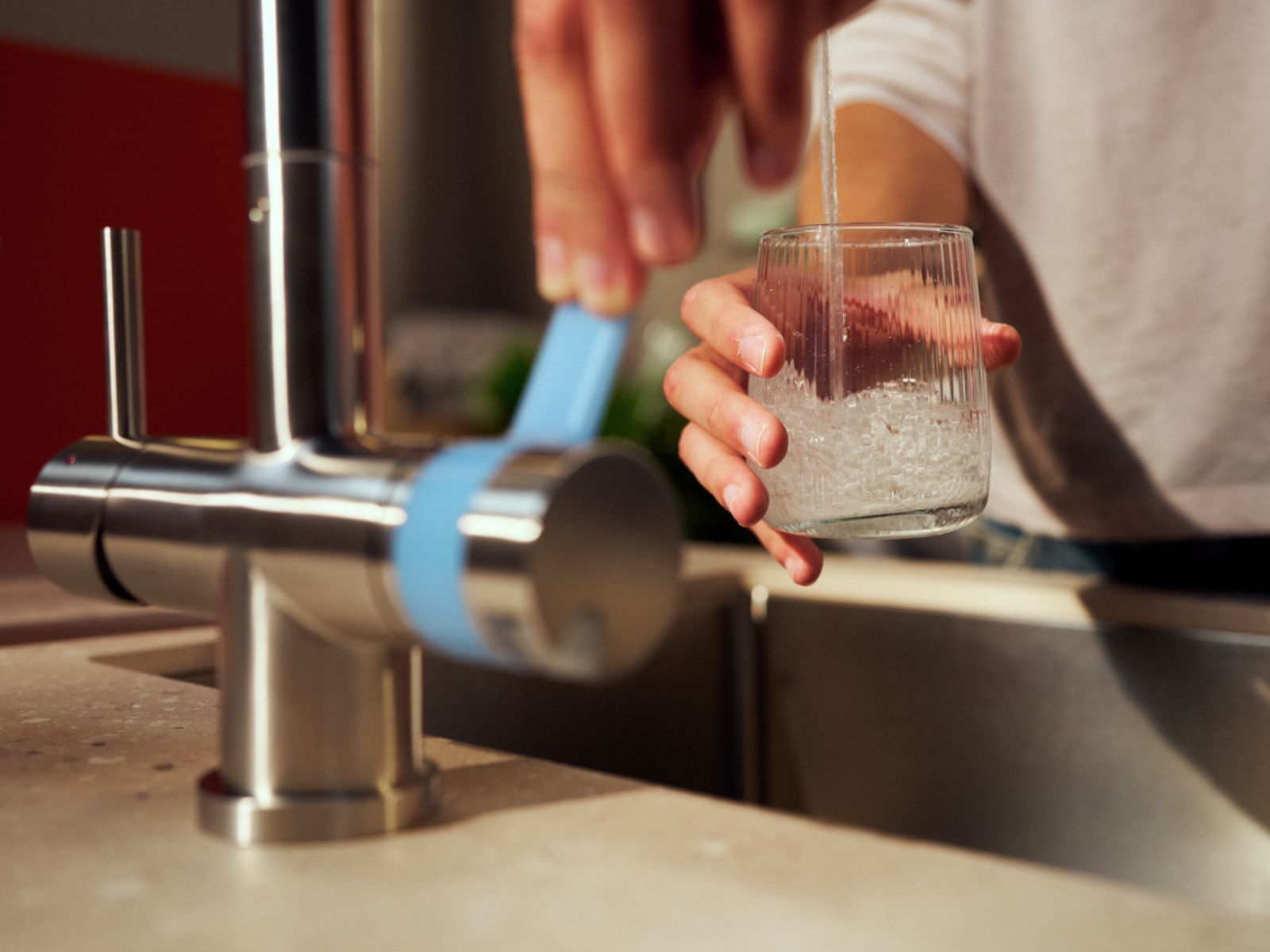 Leitungswasser trinken Mann fühlt sein Wasserglas am BRITA 3-Wege Wasserhahn auf.