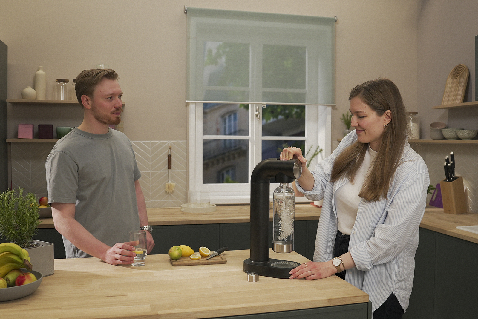 Ein Mann und eine Frau sprudeln Wasser mit BRITA sodaONE. Ein Mann und eine Frau sprudeln Wasser mit dem BRITA sodaONE Wassersprudler in einer Küche.