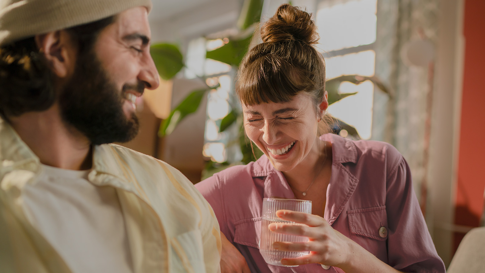 Eine junge Frau trinkt ein Glas Wasser. Eine junge Frau trinkt lachend ein Glas gefiltertes Leitungswasser.
