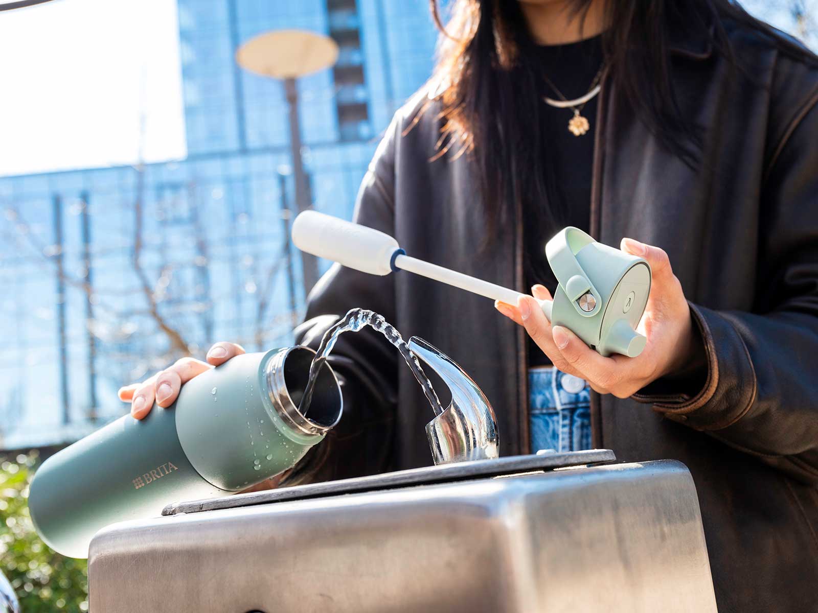 Person befüllt eine grüne BRITA LARQ Bottle an einem öffentlichen Trinkbrunnen.