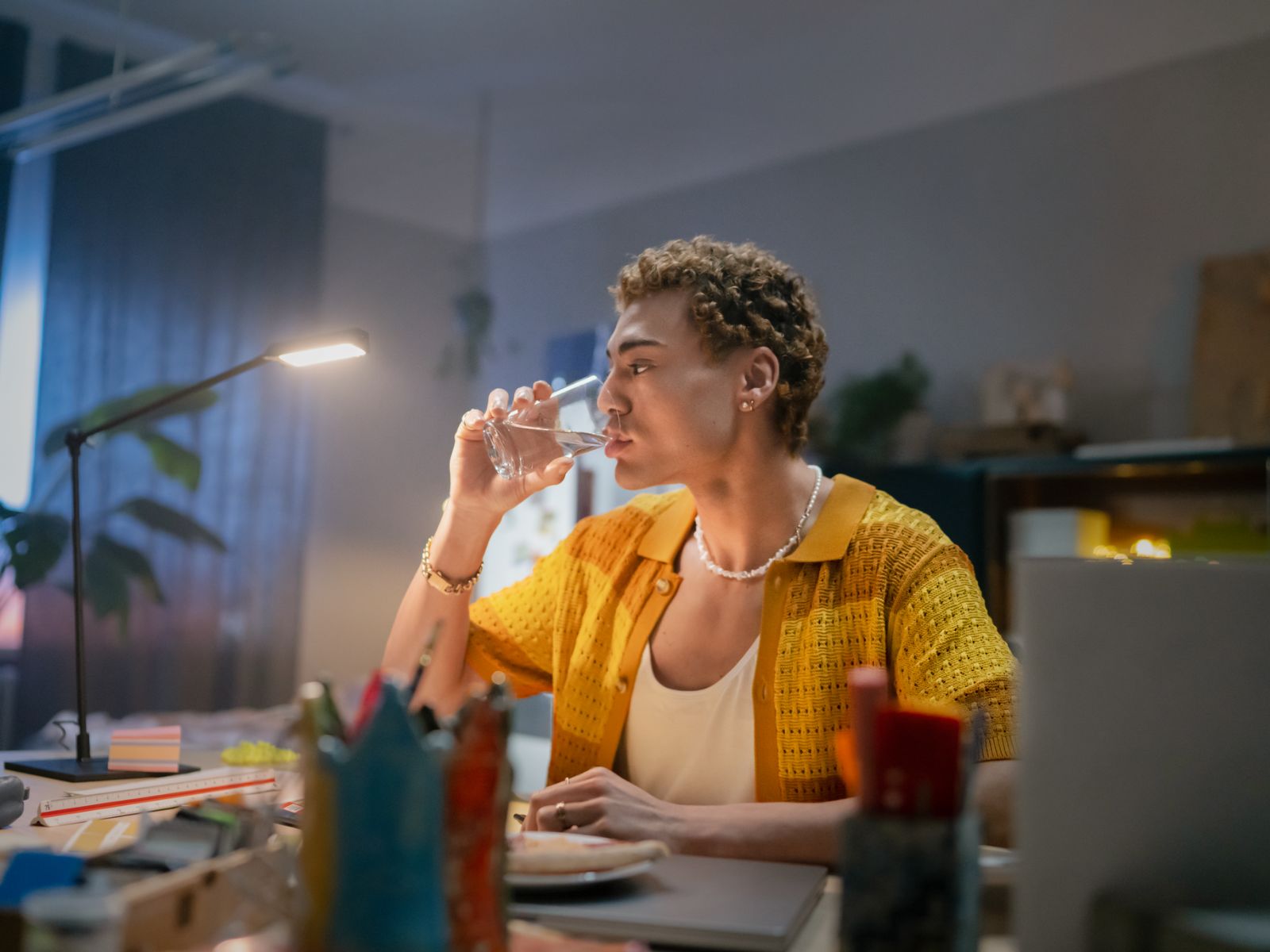 Mann am Schreibtisch trinkt Wasser aus Glas