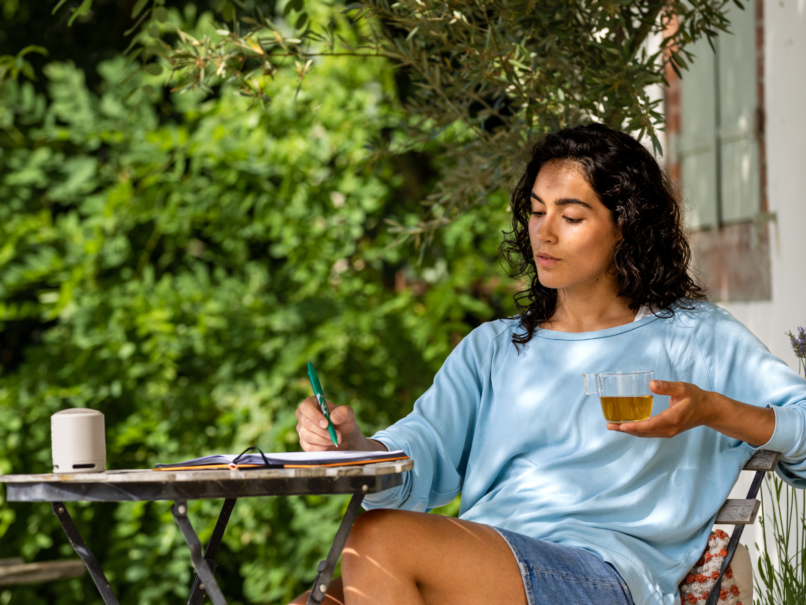 Achtsames Natur-Journaling Frau sitzt beim Journalen im Freien und trinkt Tee.