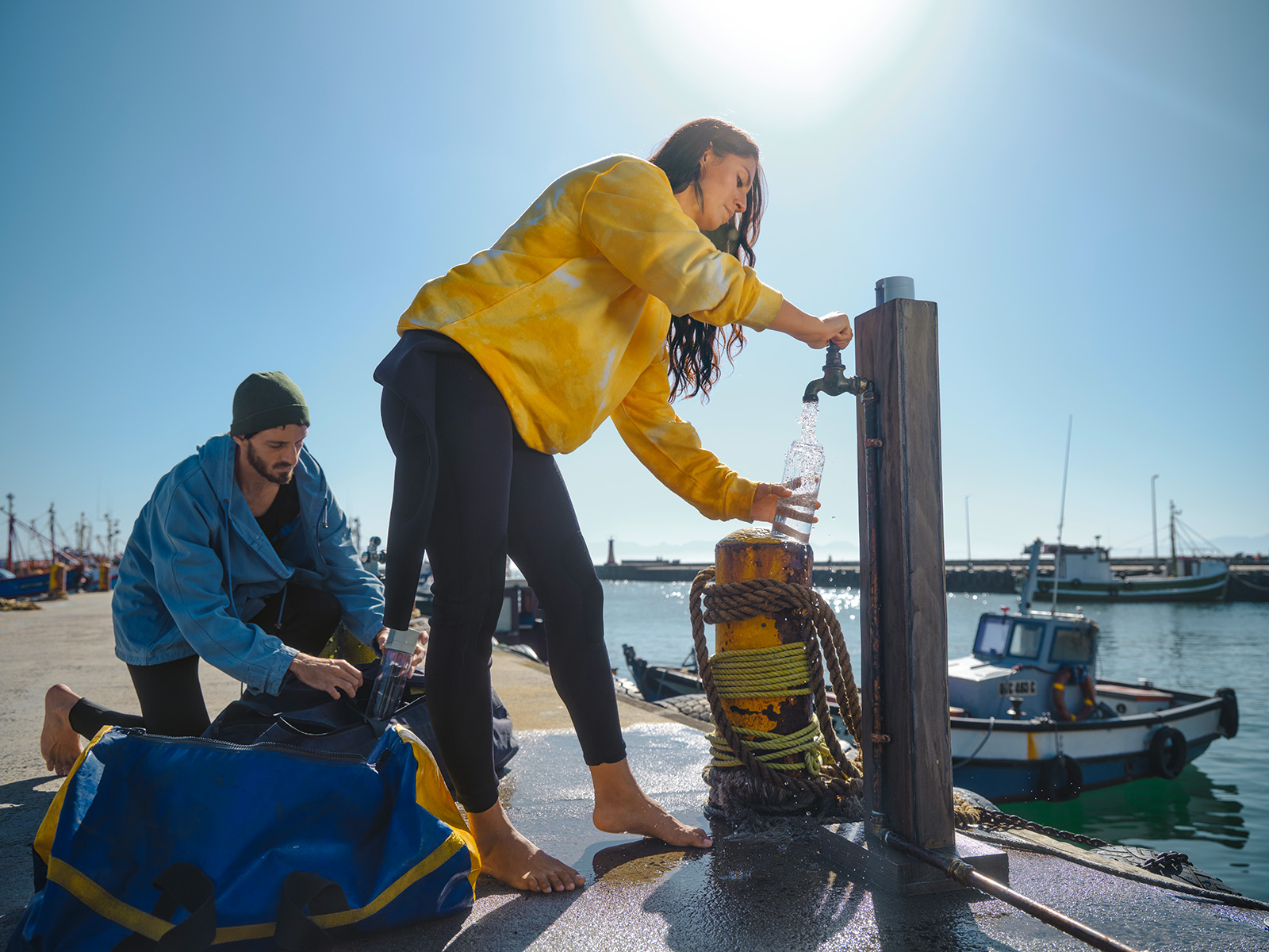 Frau füllt Wasser ab Eine Frau füllt an einem öffentlichen Wasserhahn Wasser ab