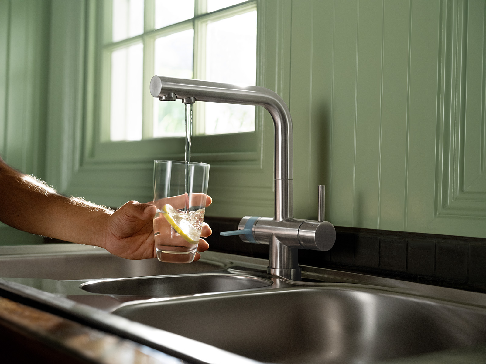 Gefiltertes Leitungswasser läuft aus dem BRITA 3-Wege-Hahn Gefiltertes Leitungswasser läuft aus dem BRITA 3-Wege-Hahn in ein Glas