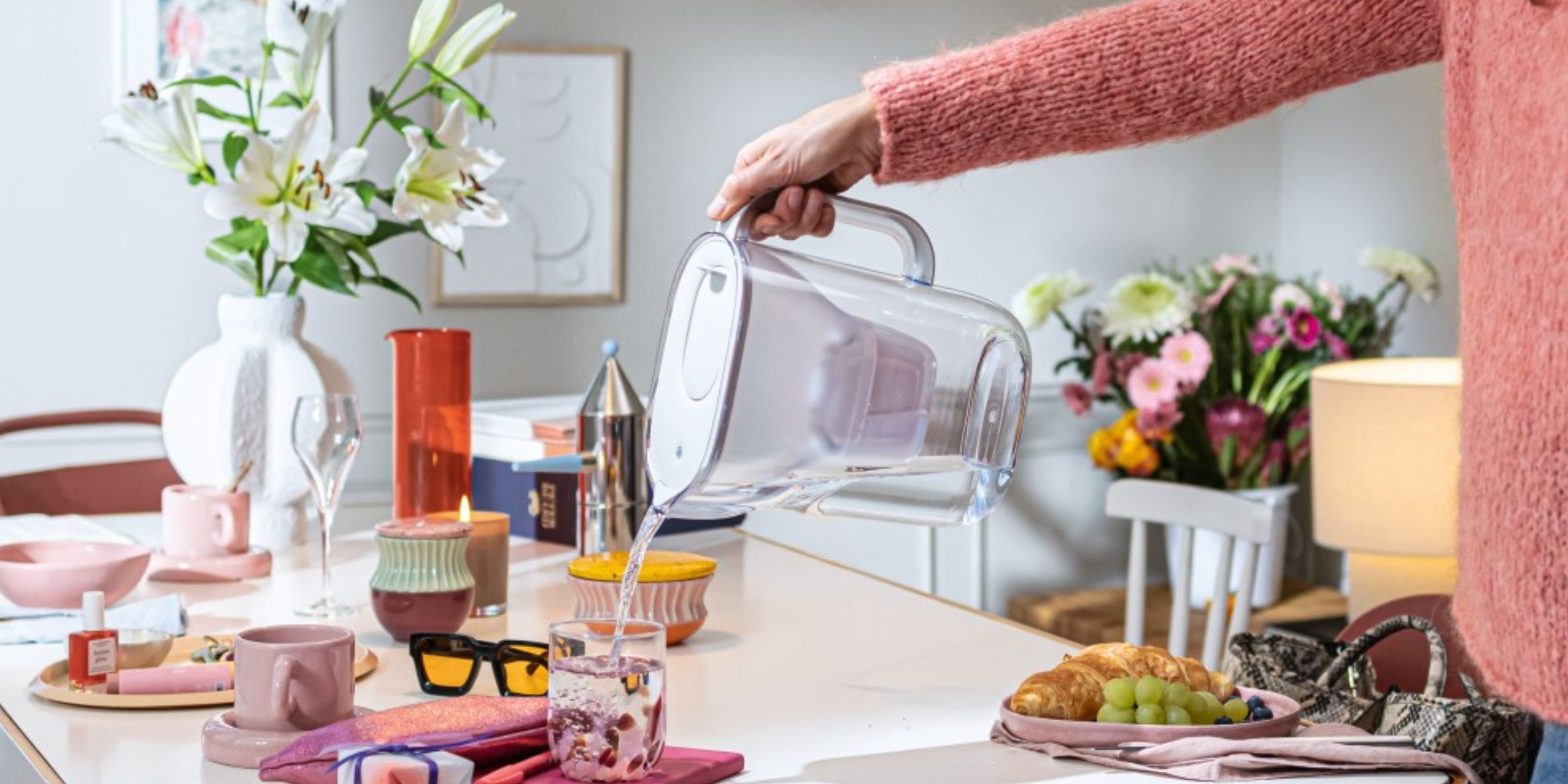 Frau schenkt aus dem BRITA Tischwasserfilter Style Essential ein Glas Wasser ein