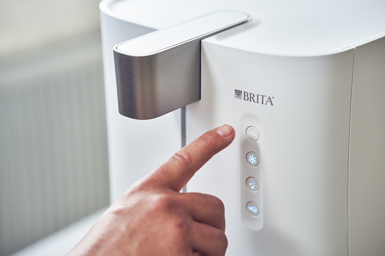 Nutzung des Wasserspenders yource pro top  Mit dem Finger wird ein Knopf des yource pro top Wasserspenders gedrückt.