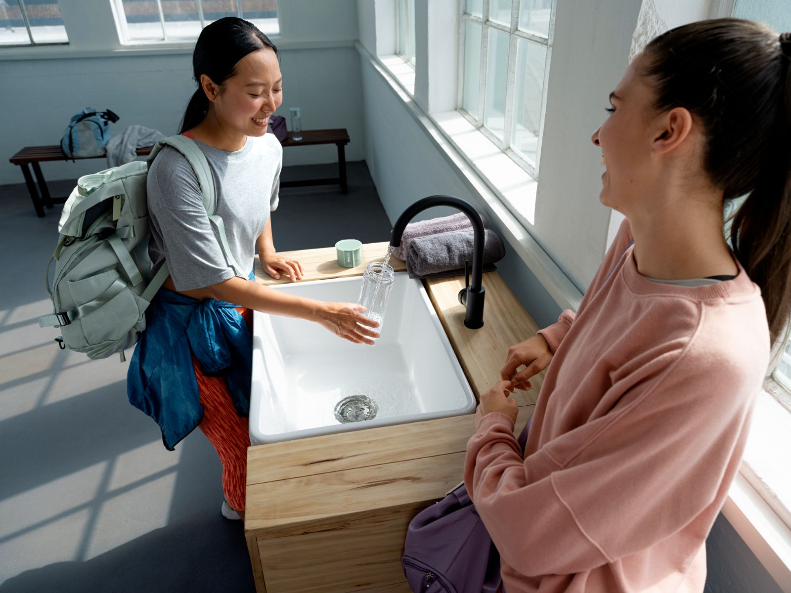 Frauen füllen Wasser mit BRITA Wasserhahn in Glas Frauen füllen Wasser mit BRITA Wasserhahn in Glas