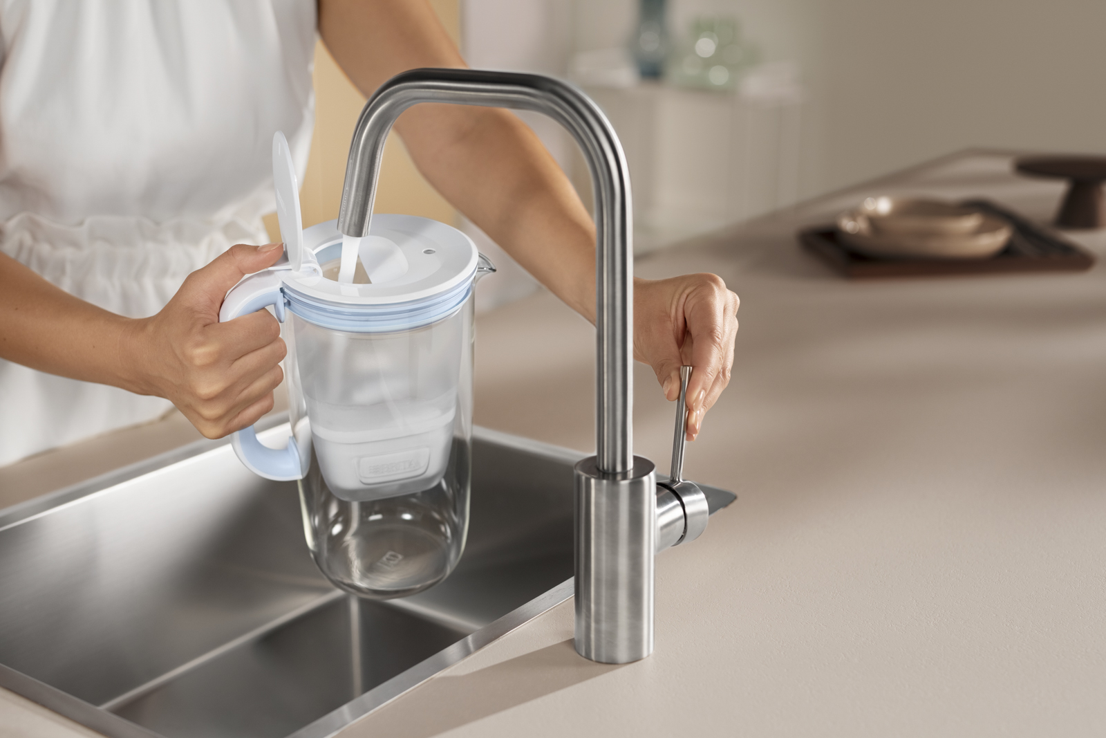 Tischwasserfilter Glas wird am Wasserhahn befüllt. Der BRITA Tischwasserfilter Glas in Blau wird am Wasserhahn befüllt.
