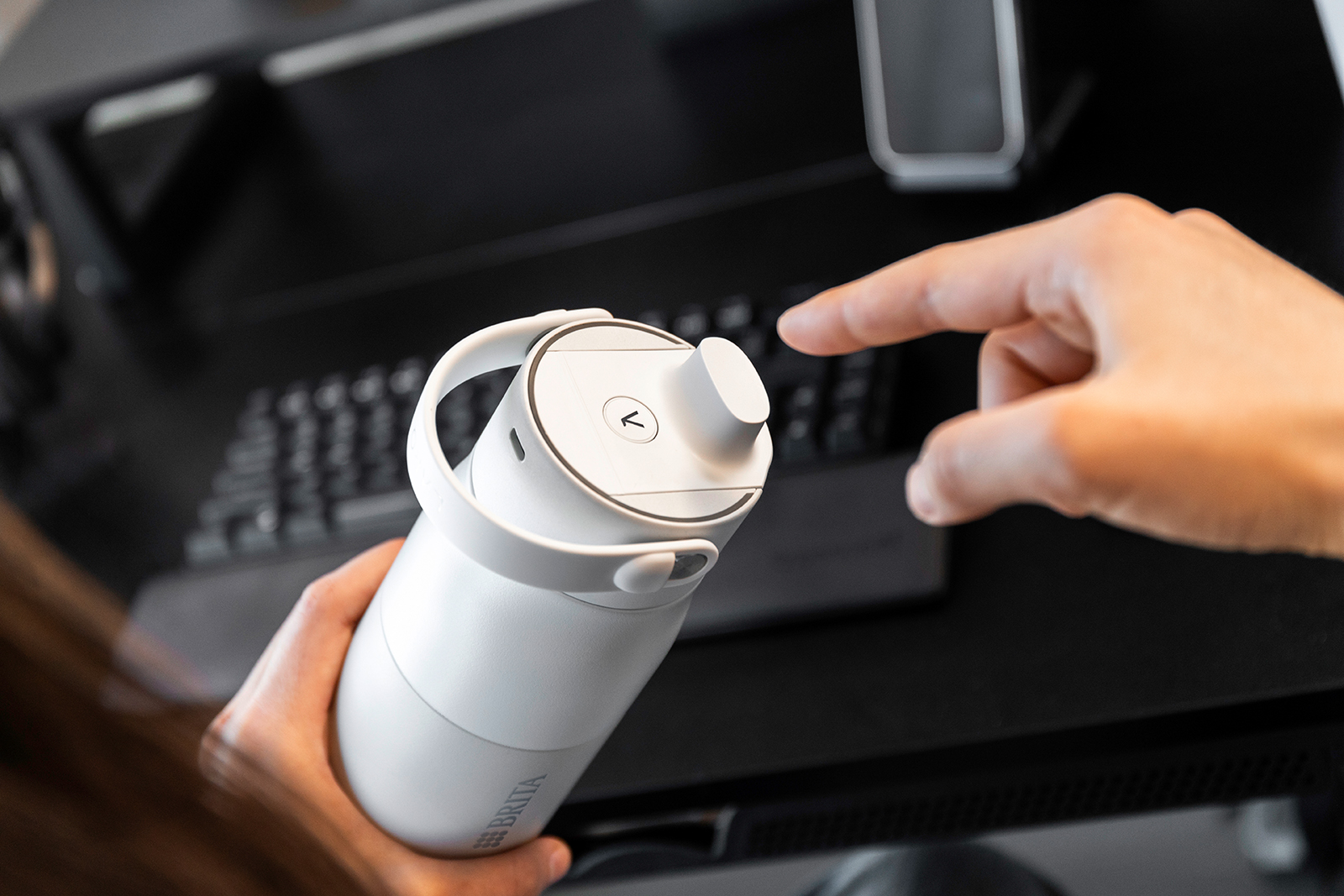 PureVis Reinigung automatisch oder auf Knopfdruck Eine Person ist gerade dabei die Reinigungsfunktion der BRITA LARQ iQ Flasche zu aktivieren.