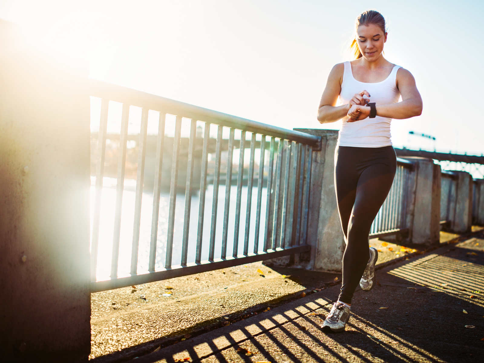 Joggen für Anfänger: Trainingsplan Frau startet mit dem Laufen und überprüft ihren Puls mit ihrer Smart-Watch