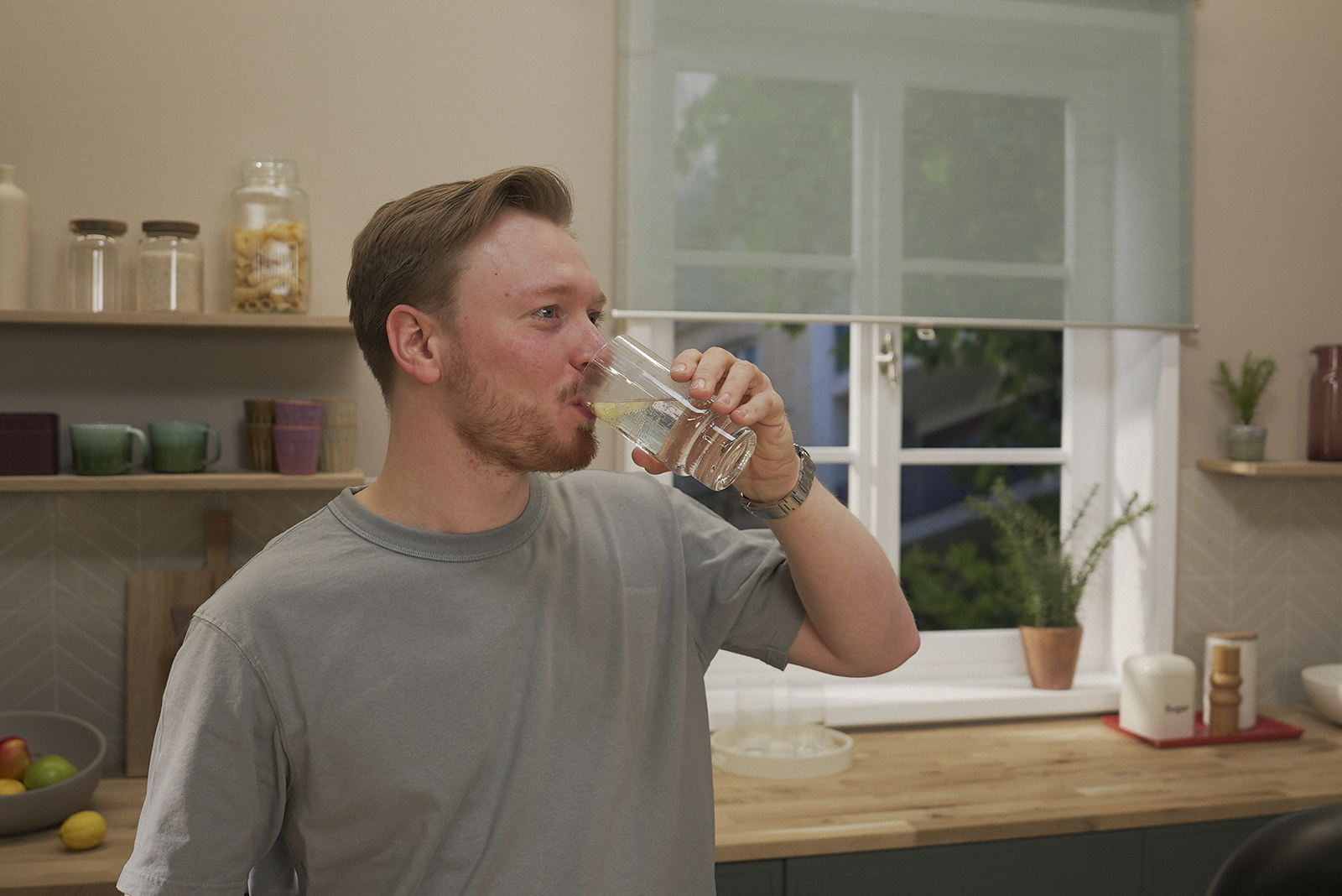 Ein Mann in braunem Pullover trinkt einen Schluck BRITA gesprudeltes Wasser. 
