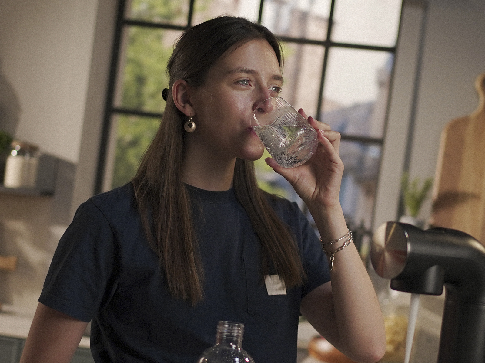 Eine Frau trinkt ein Glas Wasser in einer Küche. Eine Frau trinkt ein Glas Wasser in einer Küche.