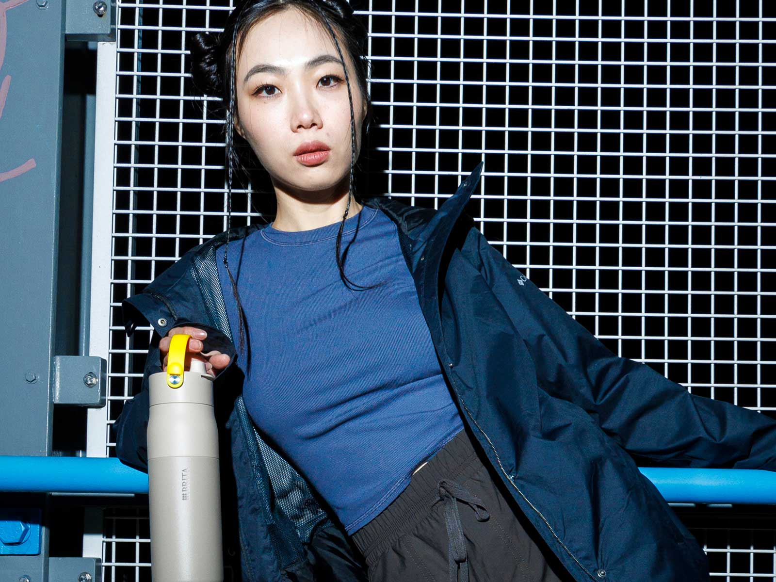 Stylische junge Frau posiert mit einer BRITA LARQ Flasche, die ein farbiges Griffband hat