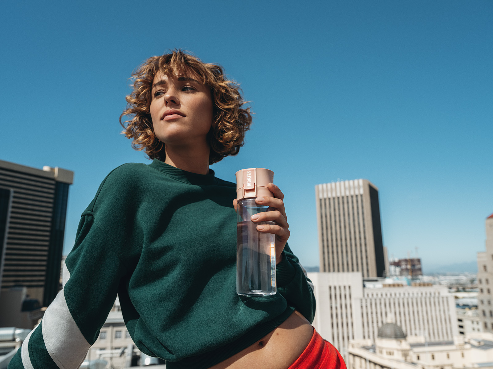 Frau vor Skyline mit Model Vital Eine brünette Frau hält die Model Vital in der Hand, hinter ihr sieht man eine Skyline.