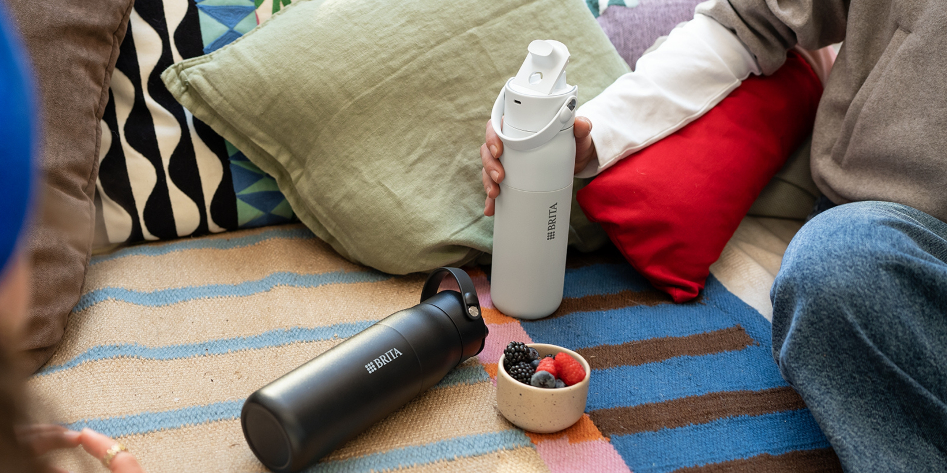 Schwarze und weiße BRITA LARQ iQ Wasserfilterflasche auf einer Couch.