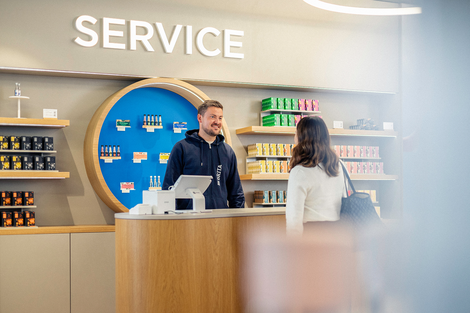 Verkäufer unterhält sich mit Kundin im BRITA Flagship Store Ein junger Verkäufer unterhält sich mit einer Kundin im BRITA Flagship Store.