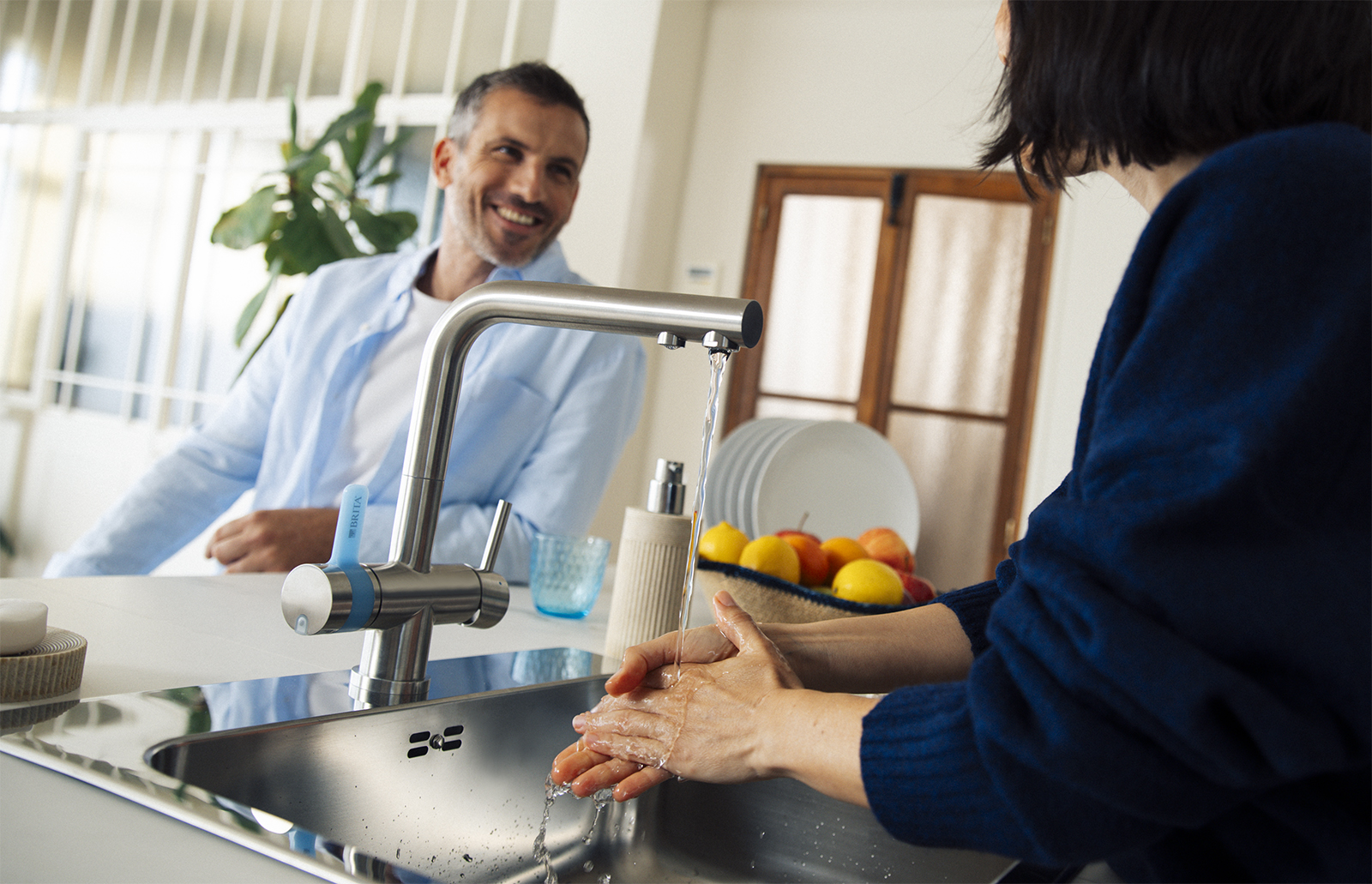 Eine Frau wäschst sich in einer Küche an der BRITA 3 Wege Küchenarmatur die Hände