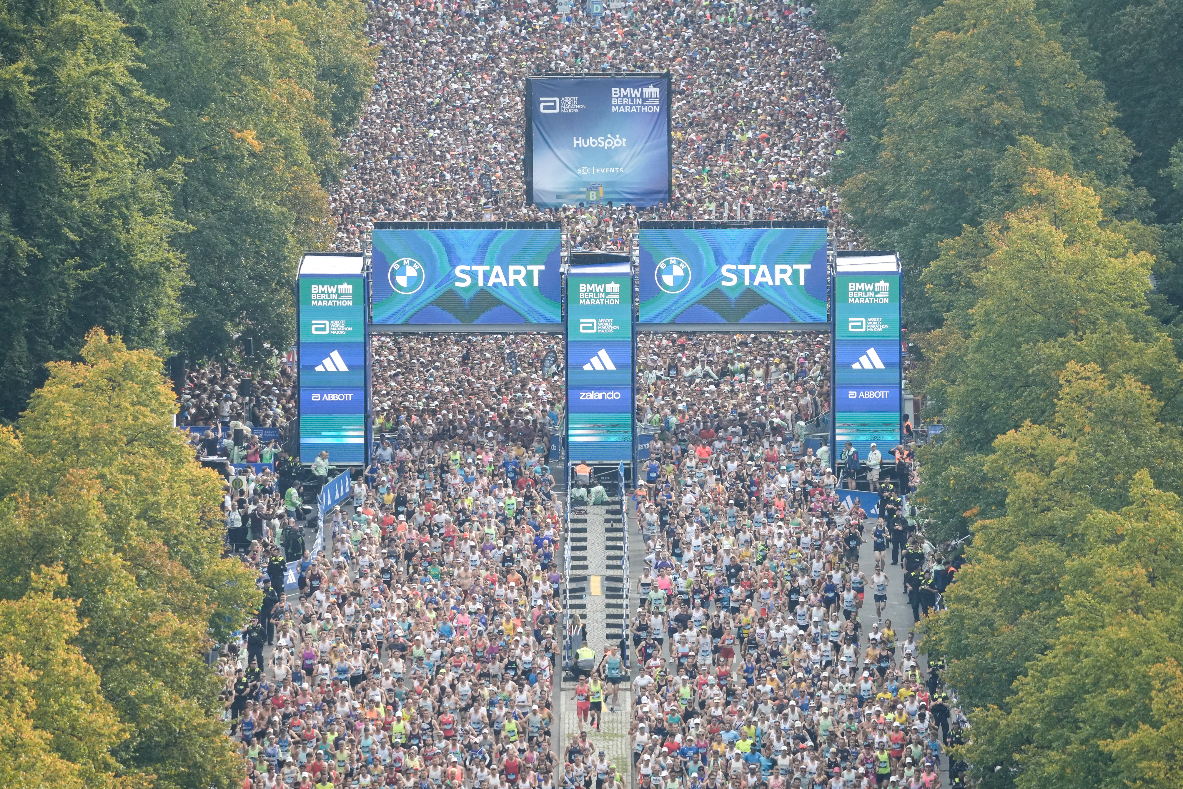 Dichte Menschenmenge am Start des BMW Berlin‑Marathons Dichte Menschenmenge am Start des BMW Berlin‑Marathons unter dem Startbogen, umgeben von Bäumen.