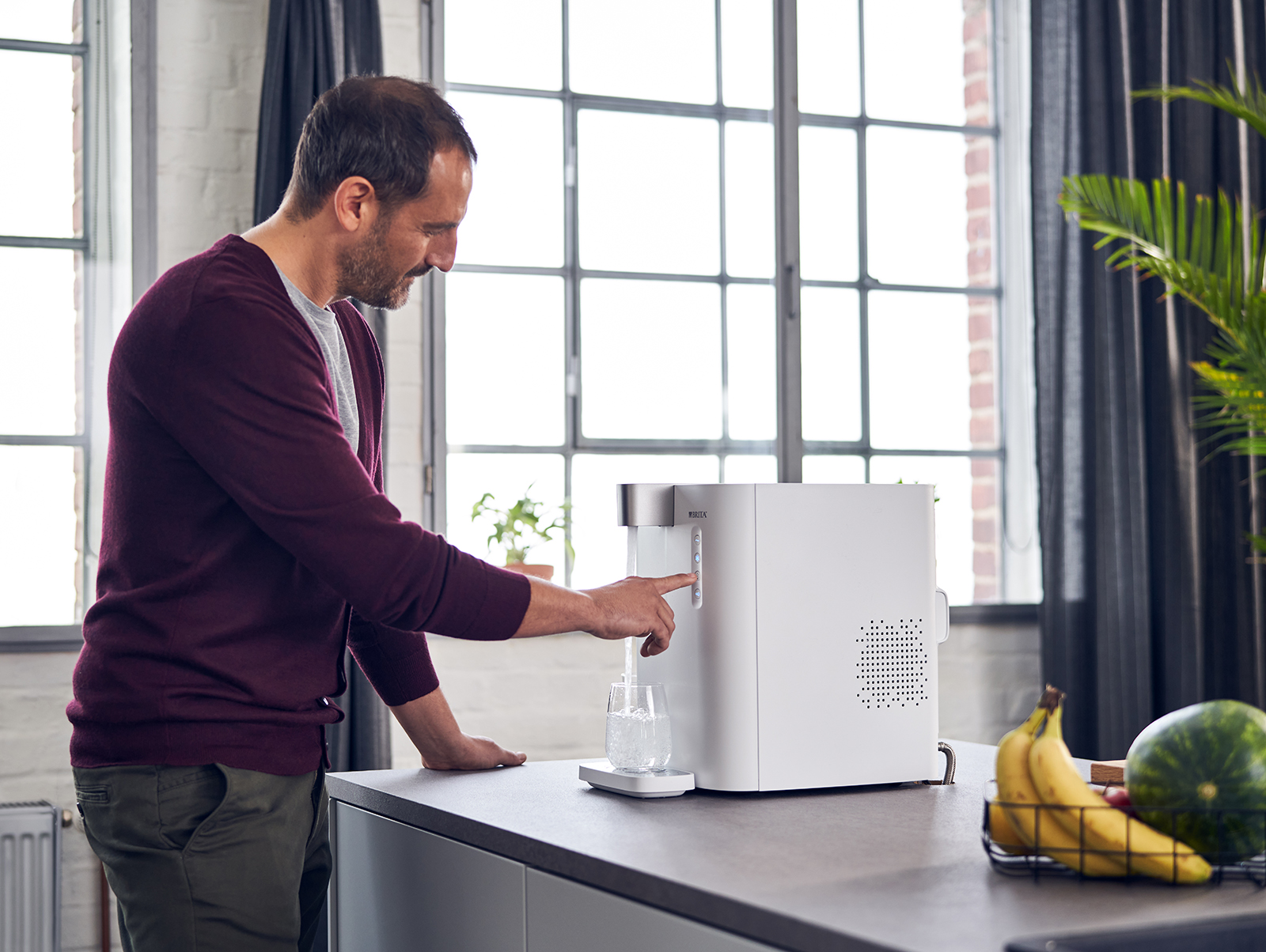 Ein Mann benutzt den Wasserspender yource pro top, um sich ein Glas Wasser einzuschenken.