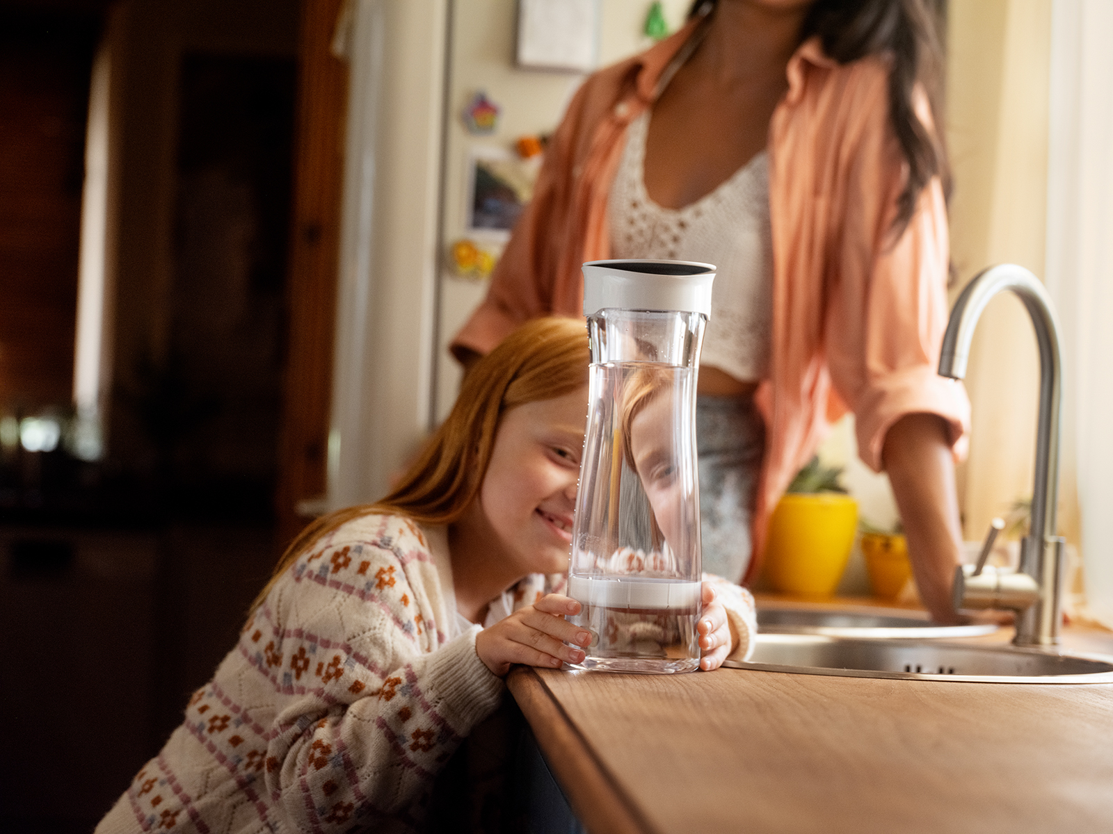 Ein Mädchen schaut sich die BRITA Wasserkaraffe mit Filter in einer Küche an.