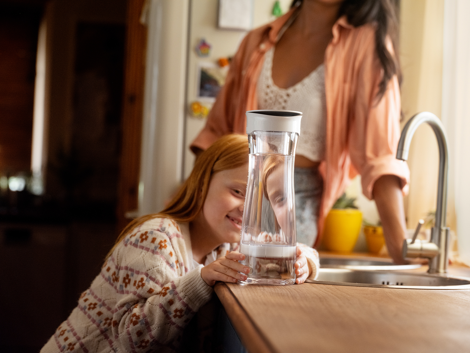 Mädchen schaut BRITA Wasserkaraffe mit Filter an. Ein Mädchen schaut sich die BRITA Wasserkaraffe mit Filter in einer Küche an.