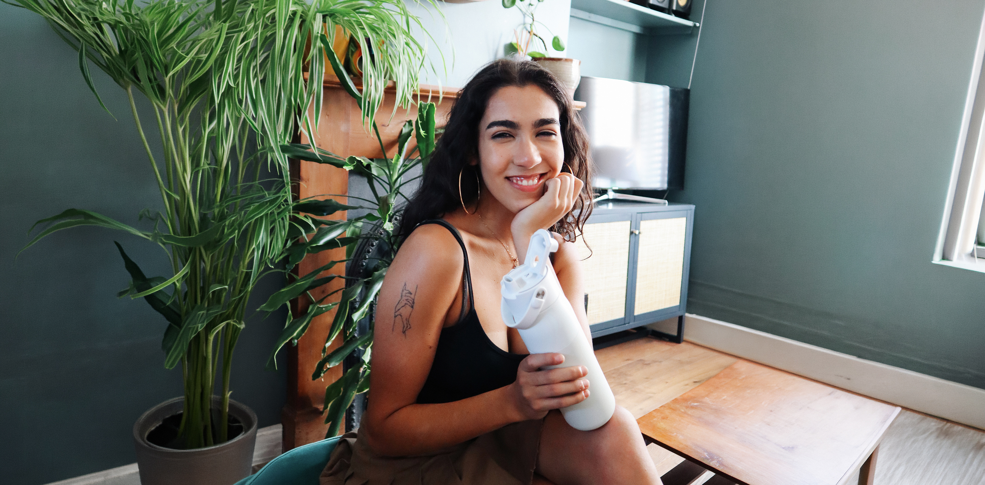 Person sitzt im Wohnzimmer und hält eine BRITA LARQ Flasche mit Deckel