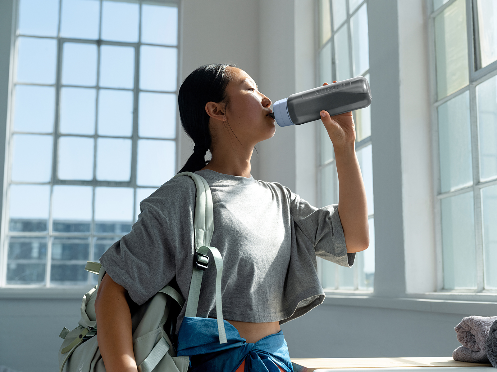 Eine junge Frau trinkt aus der Wasserfilterflasche Model Active