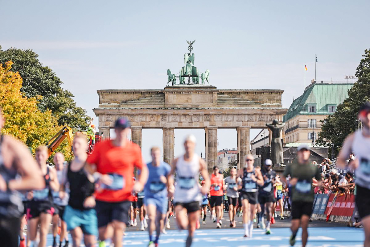 Läuferinnen und Läufer beim BMW Berlin‑Marathon auf der Zielgeraden vor dem Brandenburger Tor.
