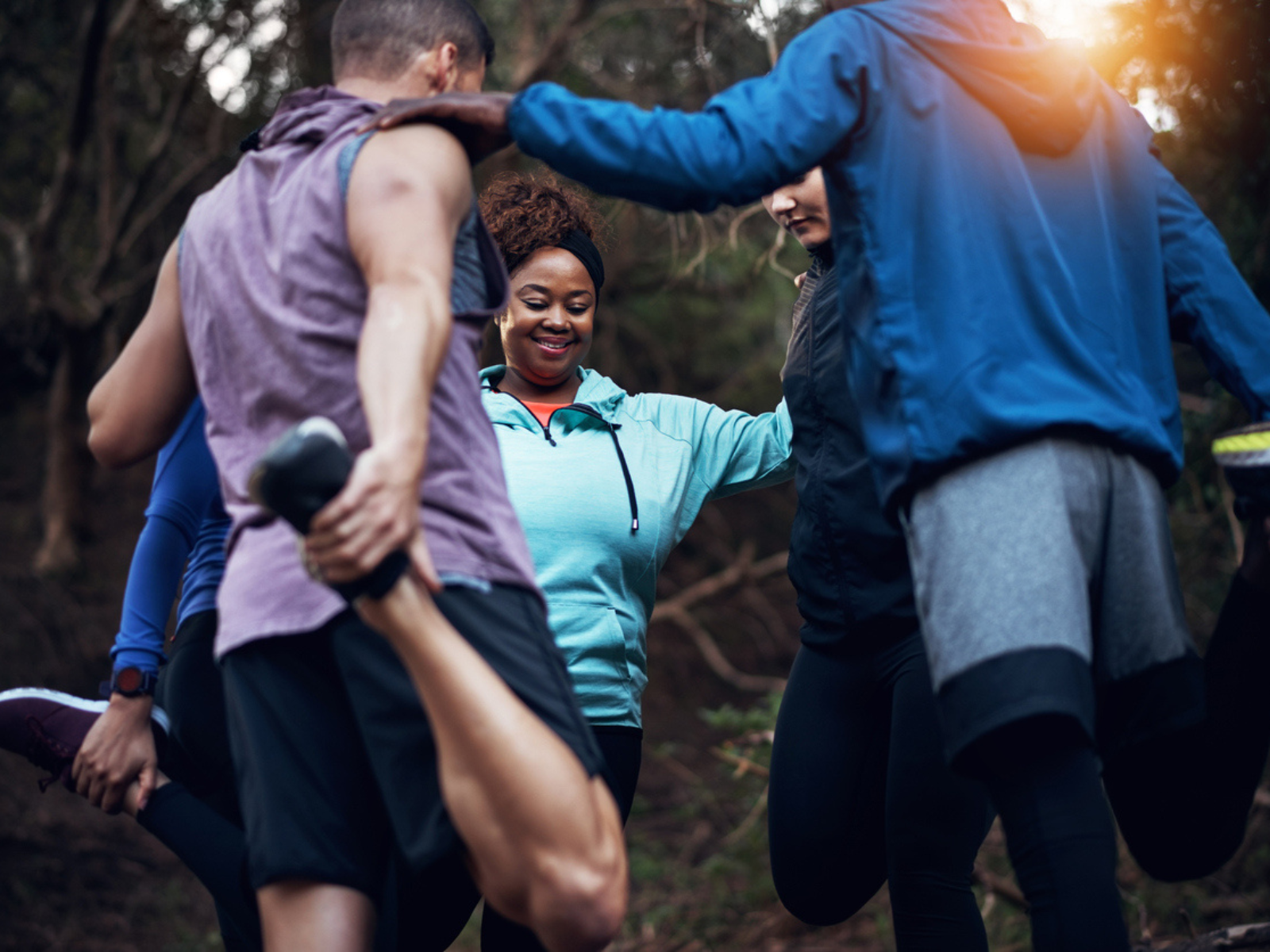 Für Läufer:innen ist Pilates ein echter Gamechanger Laufgruppe dehnt sich vor ihrem Lauf