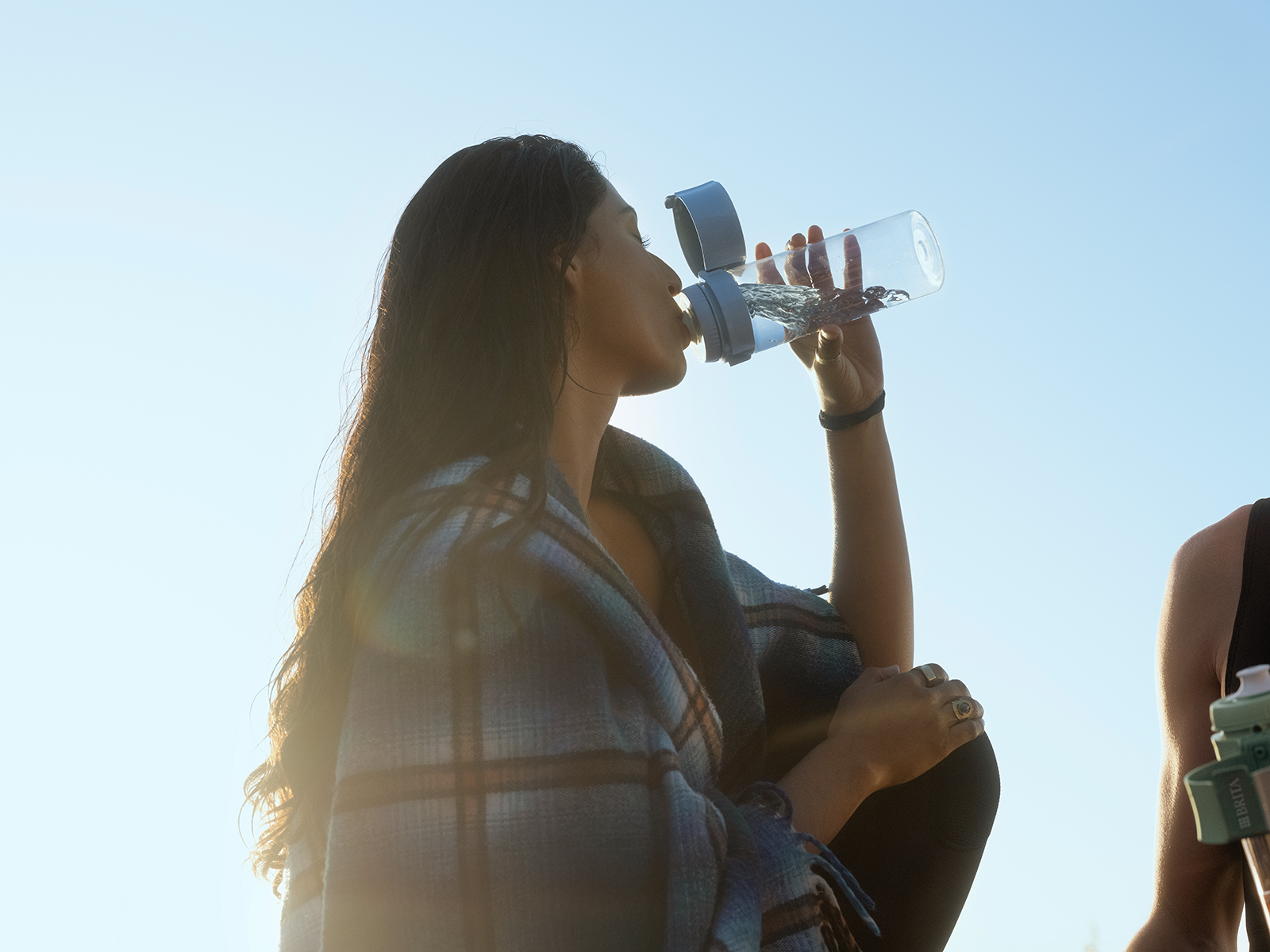 Eine Frau trinkt Wasser aus der BRITA Wasserfilterflasche Model Vital