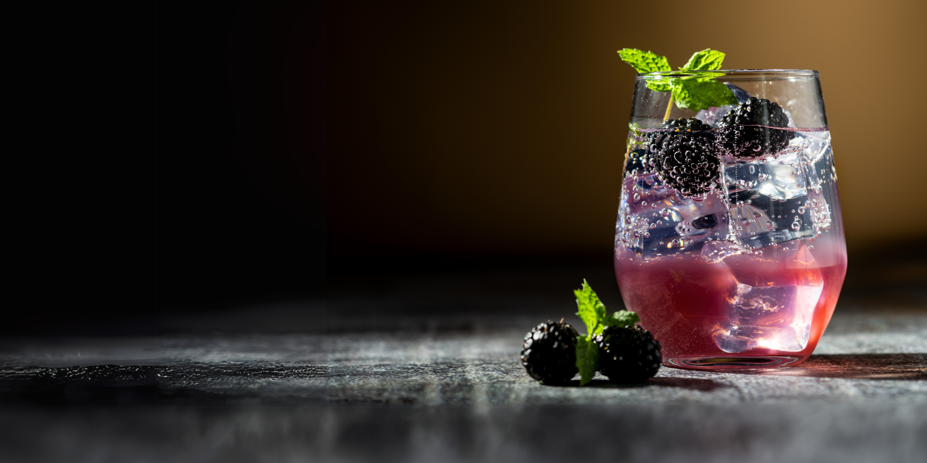 Mocktail mit Brombeeren und Minze, mit Eiswürfel und gefiltertem Wasser serviert