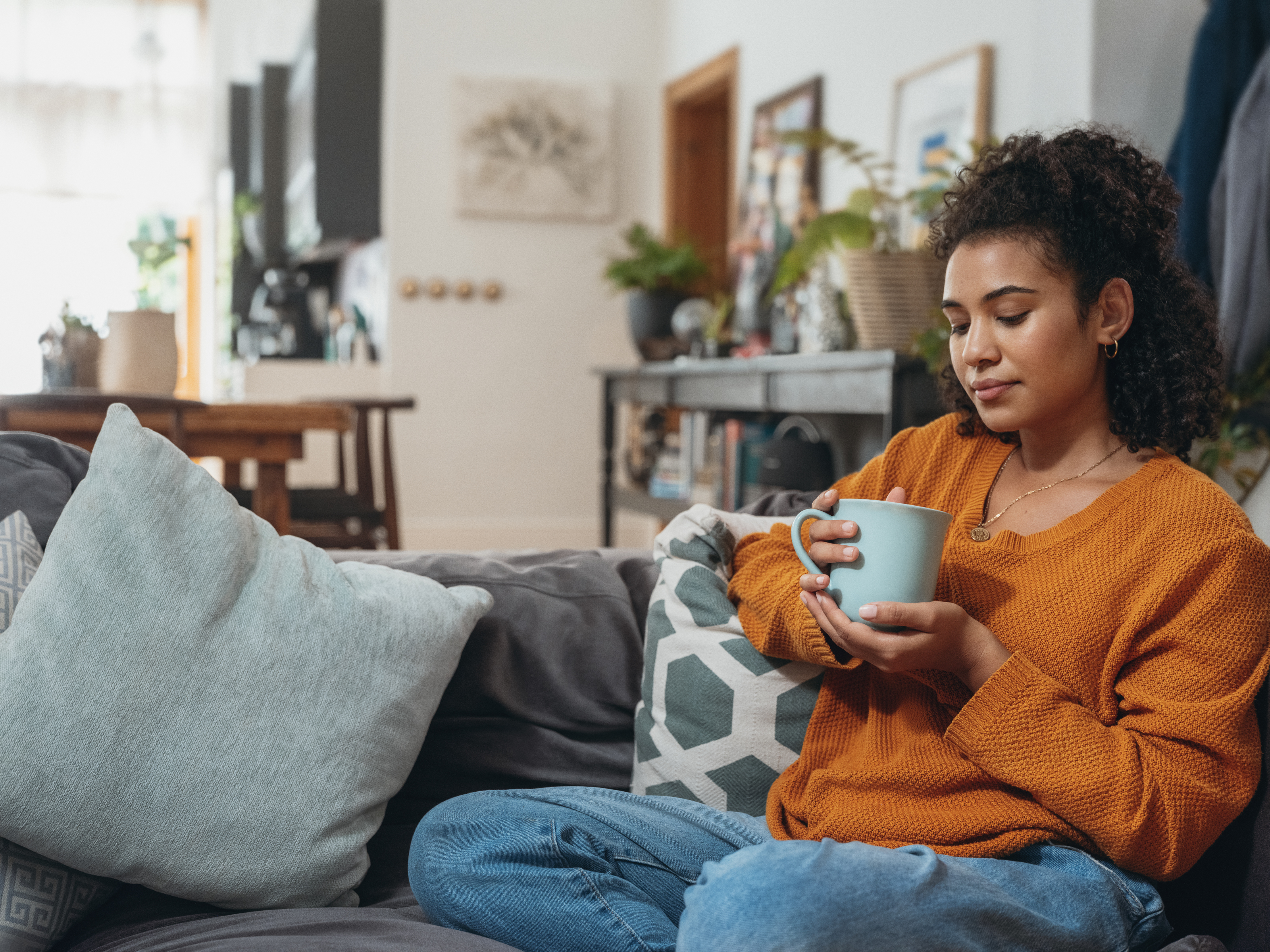 Junge Frau trinkt ein Kaffee auf dem Sofa Junge Frau chillt auf ihrer Couch mit einem Kaffee
