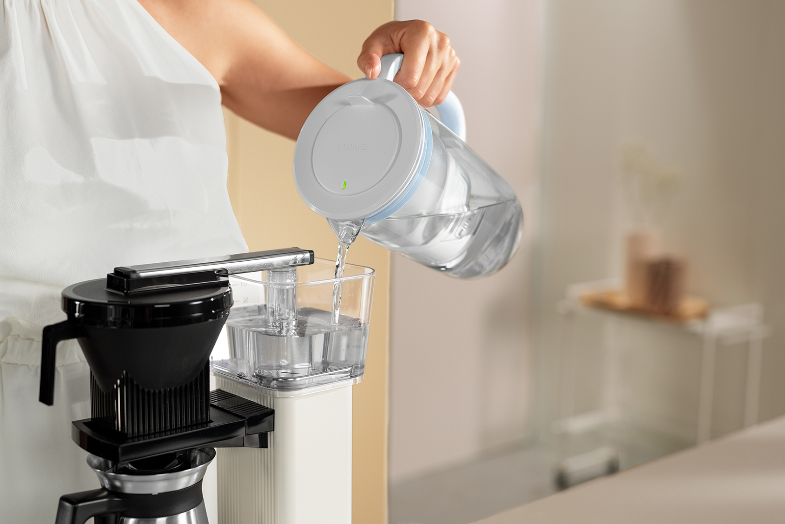 Gefiltertes Wasser wird in eine Kaffeemaschine gefüllt Gefiltertes Wasser wird mit dem Tischwasserfilter BRITA Glas in eine Kaffeemaschine gefüllt
