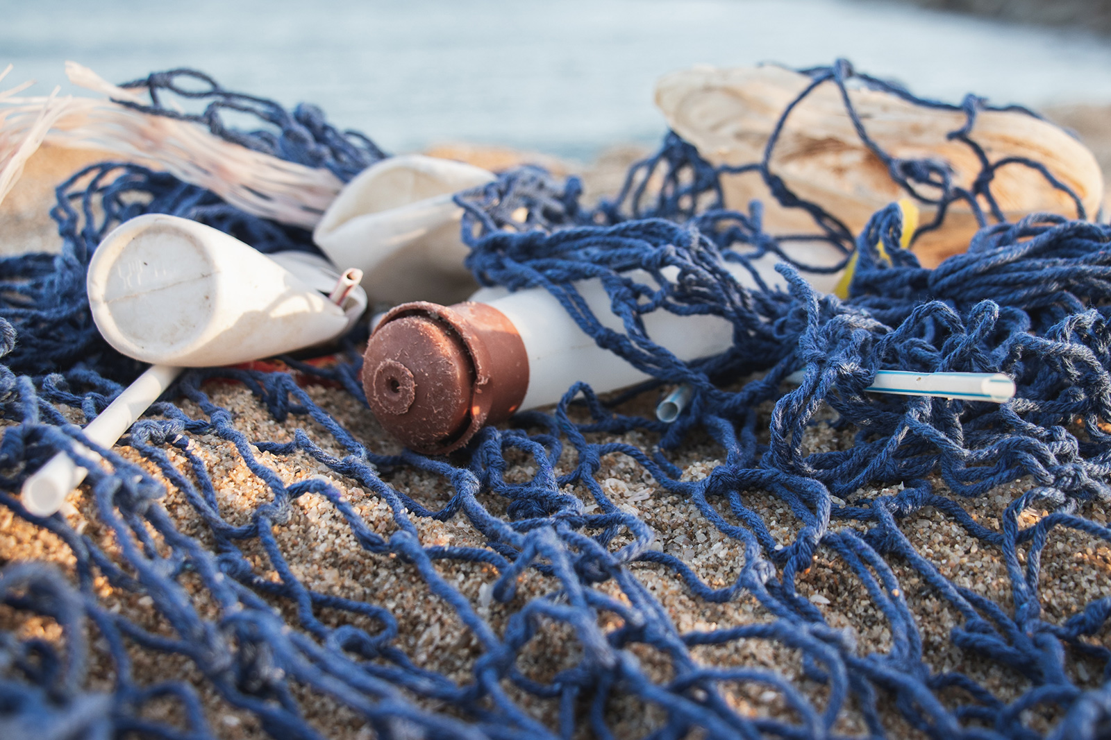 Fischernetz mit Plastikmüll am Strand Blaues Fischernetz mit Plastikflaschen am Strand