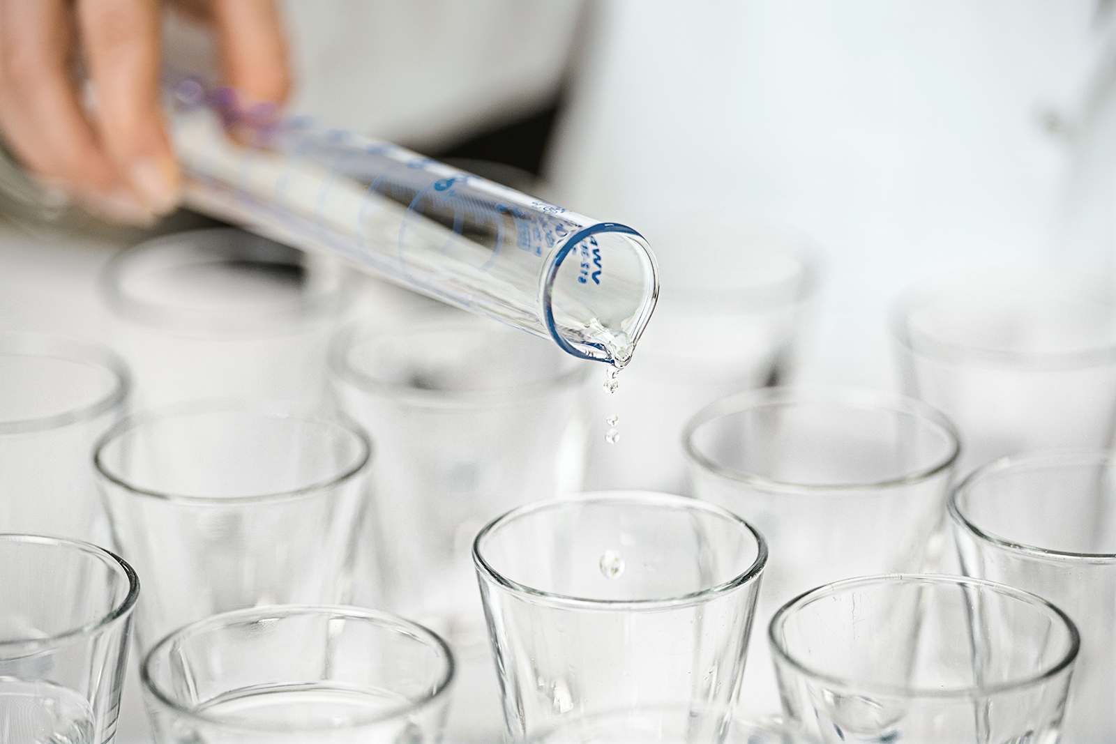 Wasser tropft aus einem Reagenzglas in ein Wasserglas Wasser tropft aus einem Reagenzglas in ein Wasserglas
