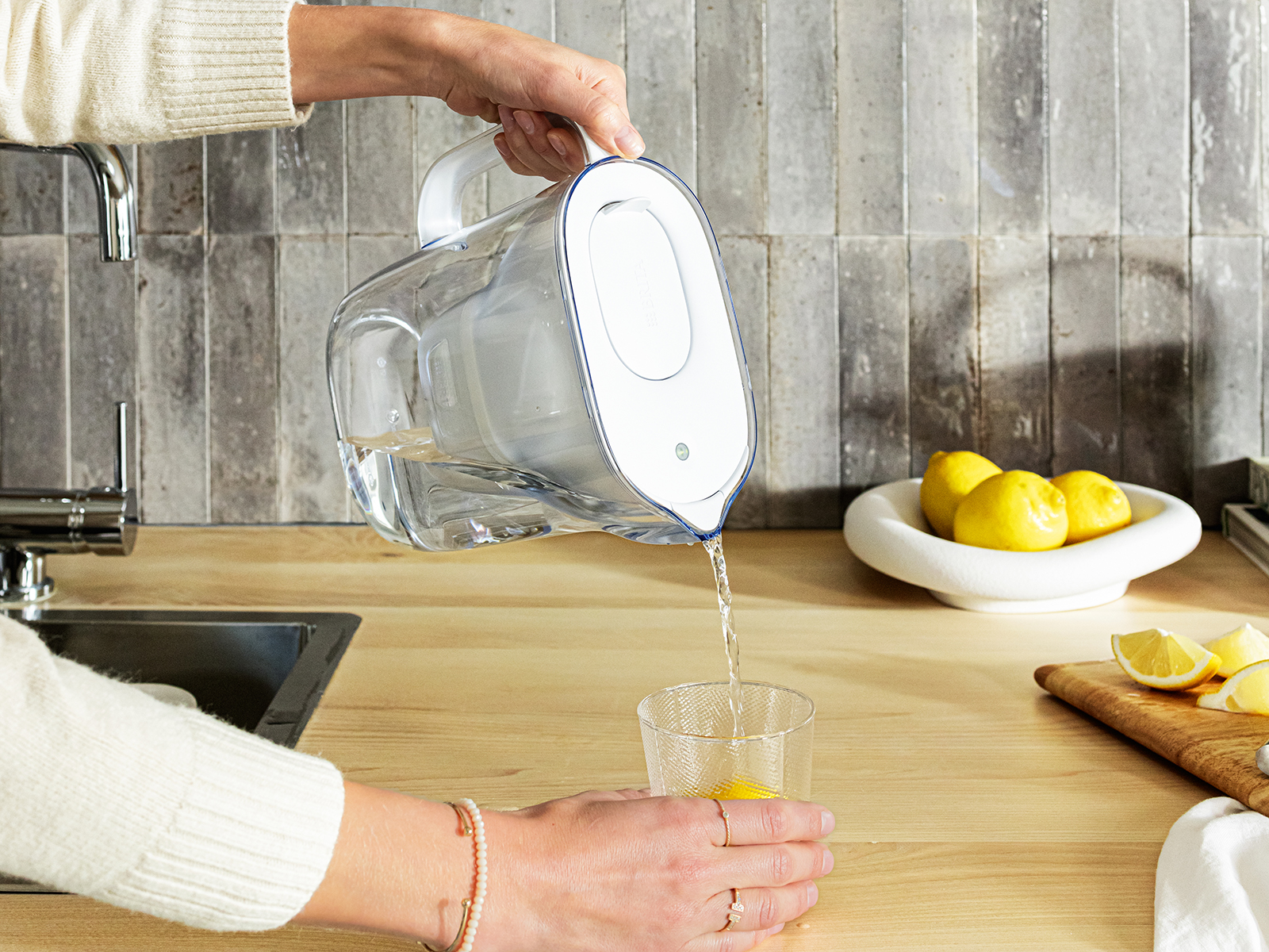 Wasser wird aus dem weißen Style Essential in ein Glas gegossen.