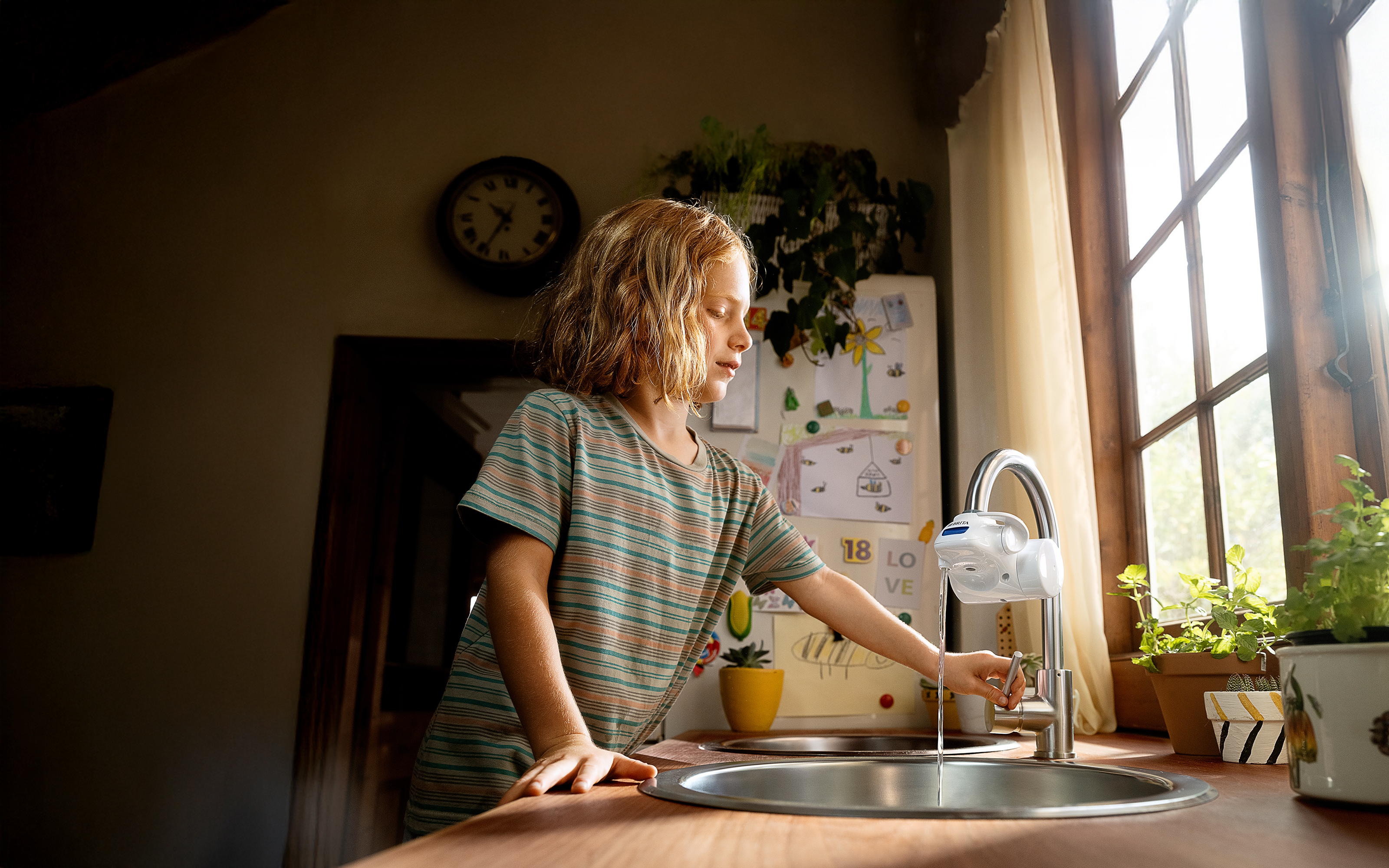 Junge benutzt ON TAP V-MF Wasserhahnfilter Ein Junge benutzt den ON TAP V-MF Wasserhahnfilter